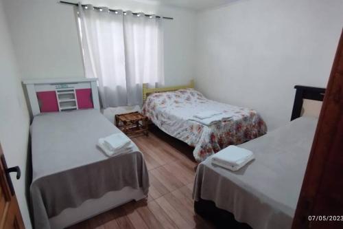 a small room with two beds and a window at Edícula familiar - Ao lado BR277 in Guarapuava
