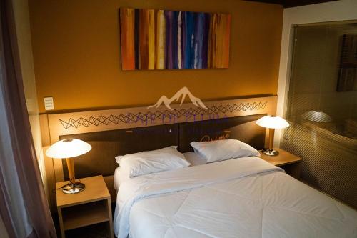 a bedroom with a white bed with two lamps at Laje de Pedra Mountain VillagePrime in Canela