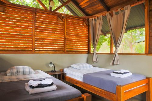 Peace Retreat Costa Rica في Playa Negra: سريرين في غرفة بجدران خشبية ونوافذ