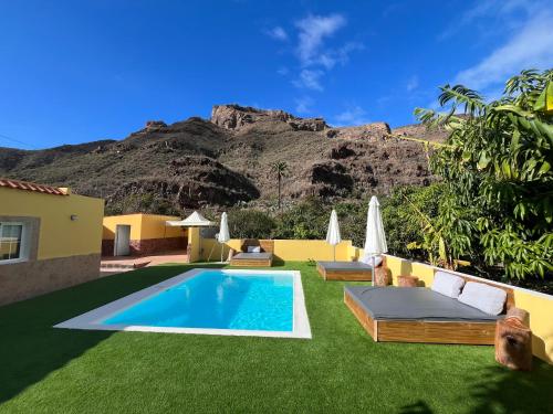 une villa avec une piscine avec une montagne en arrière-plan dans l'établissement SUNNY CARMELITO DELUXE, à Mogán