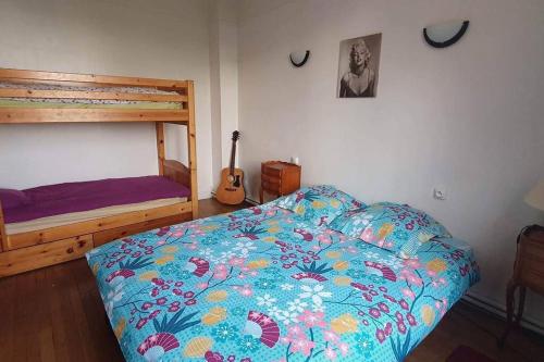 a bedroom with a bed with a colorful comforter and a guitar at Grand appartement proche Paris in Montreuil