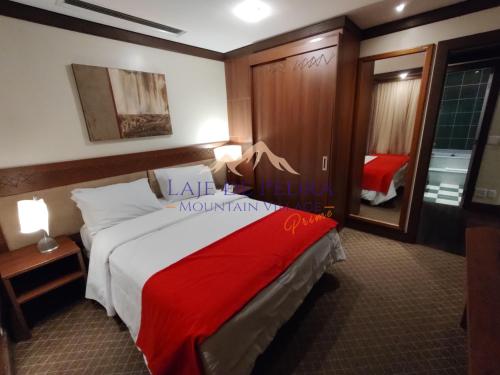 a bedroom with a bed with a red blanket on it at Laje de Pedra Mountain VillagePrime in Canela