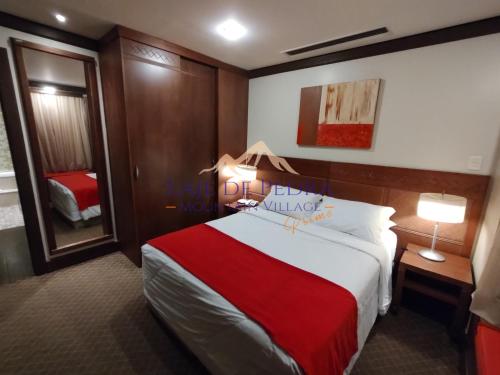 a hotel room with a large bed with a red blanket at Laje de Pedra Mountain VillagePrime in Canela