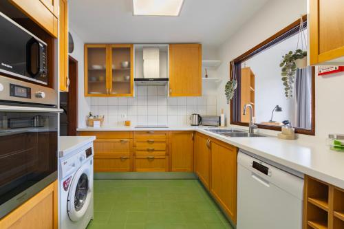 a kitchen with wooden cabinets and a green floor at Remodeled historical apartment in the City center in Fundão