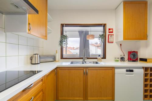 a kitchen with wooden cabinets and a sink and a window at Remodeled historical apartment in the City center in Fundão