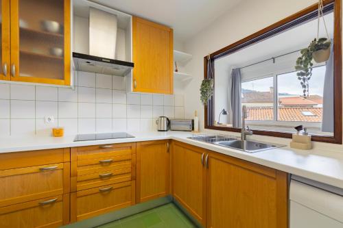 a kitchen with wooden cabinets and a sink and a window at Remodeled historical apartment in the City center in Fundão