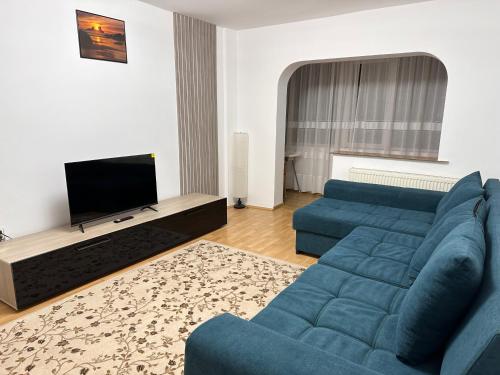 ein Wohnzimmer mit einem blauen Sofa und einem TV in der Unterkunft UrbanEscape in Onești