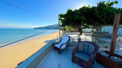 a balcony with chairs and a view of the beach at Vila Alegria in Bombinhas