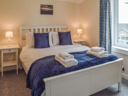 a bedroom with a bed with towels on it at Corner Cottage in Girvan