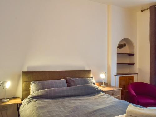 sypialnia z łóżkiem i fioletowym krzesłem w obiekcie Largs Sunset w mieście Largs