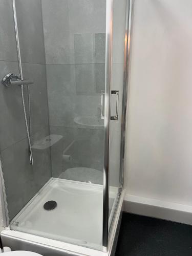 een douche met een glazen deur in de badkamer bij 2 bedroom flat in Swansea