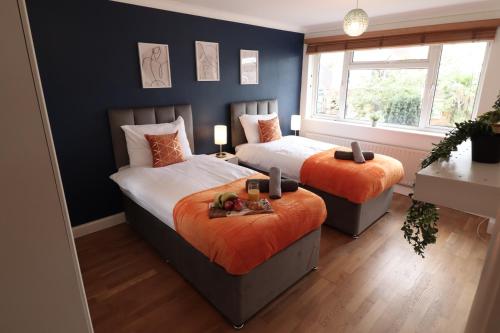 a bedroom with two beds with orange pillows at Perfect 2 Bedroom Flat Heathrow, Free Parking in Shepperton