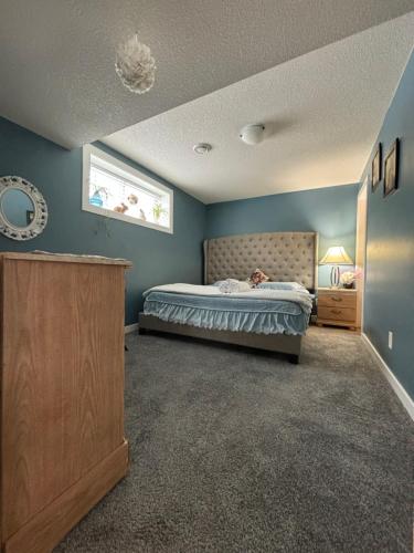 a bedroom with a bed with blue walls and a window at Happy House - Regina City in Regina