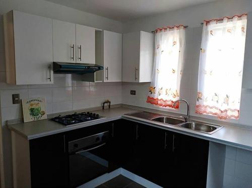 a kitchen with white cabinets and a sink at Beautiful Confortable House in Estación Colina