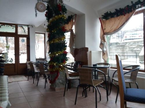 a restaurant with tables and chairs and a christmas tree at Vila Dukat Stara Planina in Crni Vrh