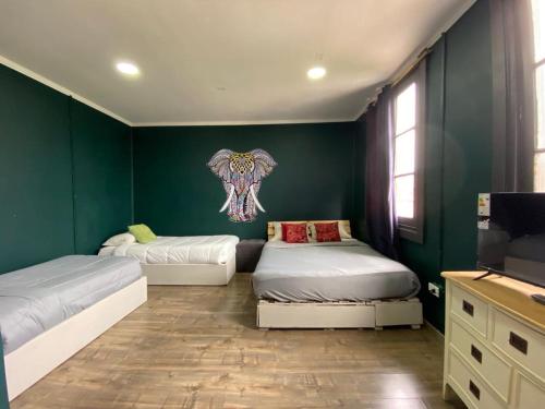 duas camas num quarto com paredes verdes em Hostal La Casona em Papudo