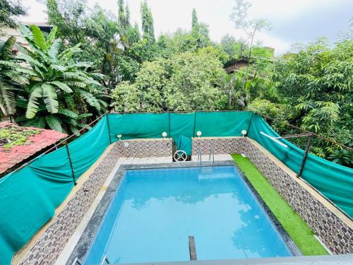 een zwembad met een groen hek eromheen bij Blue Heaven- Lonavala 2 Bhk with private pool! in Lonavala