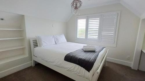 a small white bedroom with a bed with a window at Elegant Home with Seaview in Auckland