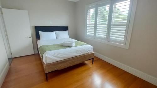 a bedroom with a bed with white sheets and a window at Elegant Home with Seaview in Auckland