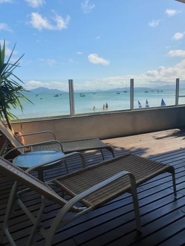 a deck with chairs and a table and a view of the beach at Vila Alegria in Bombinhas