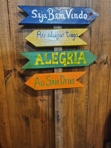 a group of directional signs on a wooden wall at Vila Alegria in Bombinhas