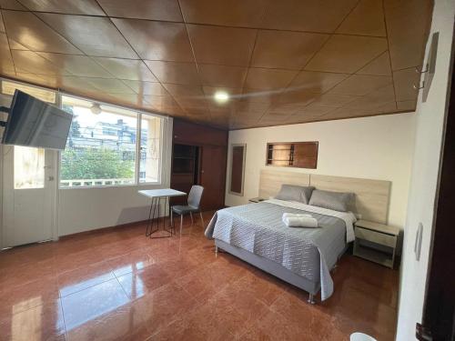 a bedroom with a bed and a table and a television at Hostel Movistar Arena in Bogotá