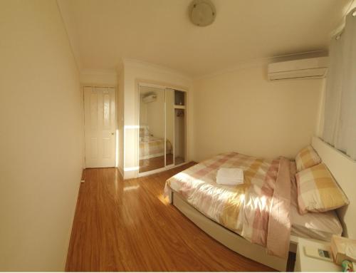 1 dormitorio con 1 cama y suelo de madera en A little bedroom for you (3), en Warwick Farm