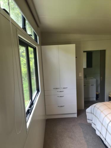 a bedroom with a white dresser and a window at Private Country Cottage in Paraparaumu