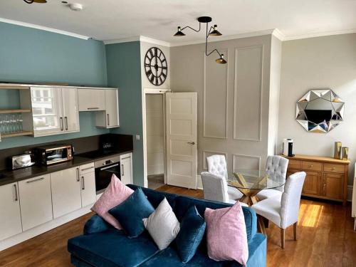 a living room with a blue couch and a kitchen at Stunning 2 bedroom Apartment in Marylebone High St in London