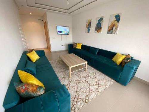 uma sala de estar com um sofá verde e uma mesa em appartements Mohammedia/mansouria em Pont Blondin
