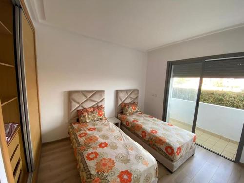 Duas camas num pequeno quarto com uma janela em appartements Mohammedia/mansouria em Pont Blondin