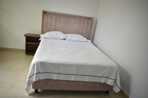 een bed met witte lakens en kussens in een slaapkamer bij Casa Campo Villa Rosa in Valledupar
