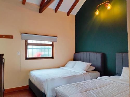 2 camas en una habitación con una pared verde en Hotel PiedradeLuna, en Villa de Leyva