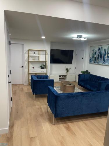 ein Wohnzimmer mit blauen Sofas und einem Flachbild-TV in der Unterkunft Stylish 2 Bedroom suite in SW Edmonton close to Windermere and Edmonton International Airport in Edmonton