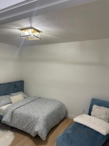 1 dormitorio con 1 cama y 1 sofá azul en Stylish 2 Bedroom suite in SW Edmonton close to Windermere and Edmonton International Airport en Edmonton