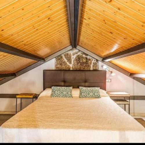 um quarto com uma cama grande e tectos em madeira em Villa Marita 1900 em Bueu