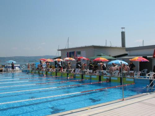 a large swimming pool with people sitting under umbrellas at Butul Apartment in Koper