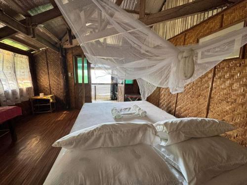 a bedroom with a bed with a mosquito net at Liberty's Community Lodge and Diving in Dumaguete