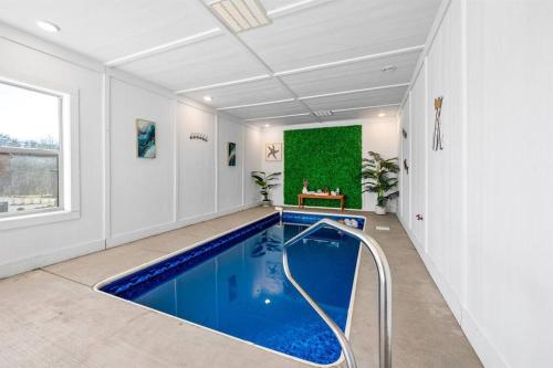 een zwembad in een witte kamer met een groene muur bij New Listing! Indoor Private Heated Pool, Less than 2 miles from Dollywood, Walk to Parkway, 4 Ensuite Bedrooms Sleeps 14, Dog Friendly, Game Room with TV, Arcade and Foosball, Hot Tub, BBQ, Smart TV and Wifi, Fully Loaded Kitchen, Washer and Dryer in Pigeon Forge