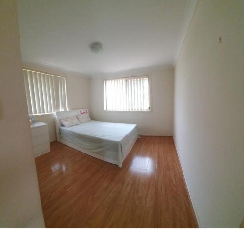 a white bedroom with a bed and a window at A cosy private bedroom for you (2) in Warwick Farm