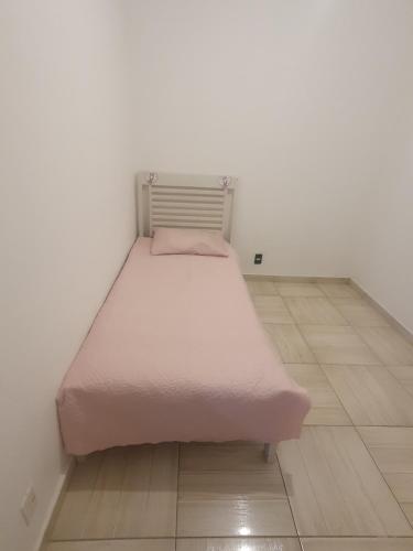 Apto. Campolim a 100mts do shopping Iguatemi في سوروكابا: سرير في غرفة مع بطانية وردية عليه