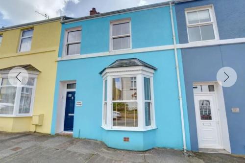 a blue and yellow house with a white door at Honey Cottage in Pembrokeshire