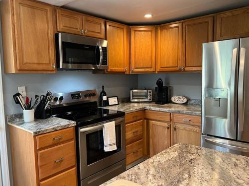 una cocina con armarios de madera y electrodomésticos de acero inoxidable en Beautifully Acquainted Home. Close to DT GSO! en Greensboro
