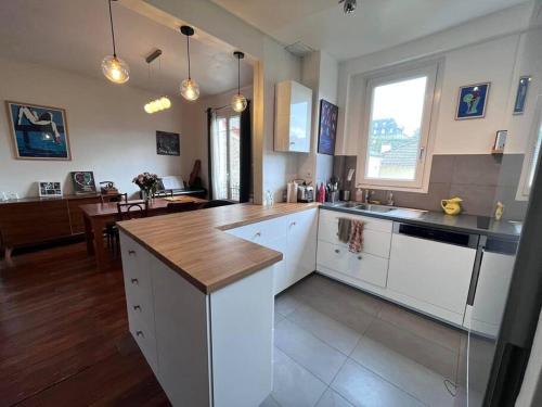 une cuisine avec des armoires blanches et un comptoir en bois dans l'établissement Charmant appartement familial avec jardin, à Sèvres
