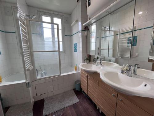 une salle de bain avec deux lavabos, une baignoire et un miroir dans l'établissement Charmant appartement familial avec jardin, à Sèvres