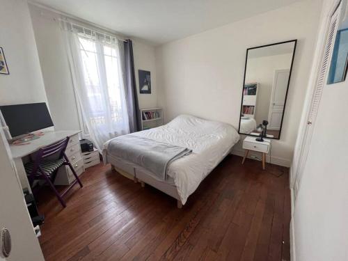 une chambre avec un lit, un bureau et un miroir dans l'établissement Charmant appartement familial avec jardin, à Sèvres