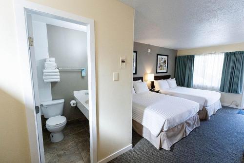 ケロウナにあるシエスタ スイーツのベッド2台とバスルームが備わるホテルルームです。