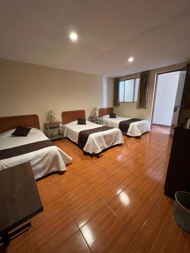 una camera con tre letti e un pavimento in legno di Hotel Tito ad Arequipa