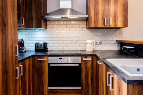 a kitchen with wooden cabinets and a black dishwasher at Mont Blanc - Emplacement n1 au centre d'Annecy in Annecy