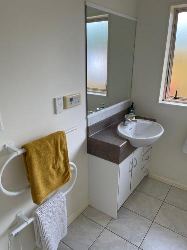 a white bathroom with a sink and a mirror at Spacious Home in Paraparaumu